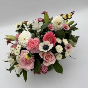 Make Me Blush floral arrangement featuring pink roses, white anemones, pink carnations, dahlias, and seasonal blooms with a butterfly accent by Sassafraz Flowers, Galena, Ohio.