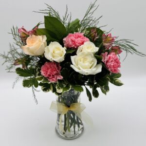 Pink Silk floral arrangement featuring ivory and blush roses, pink carnations, pink alstroemeria, and lush greenery in a clear glass vase with a gold ribbon by Sassafraz Flowers, Galena, Ohio.